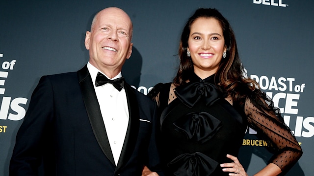 Emma and Bruce posing and smiling at the camera on a red carpet