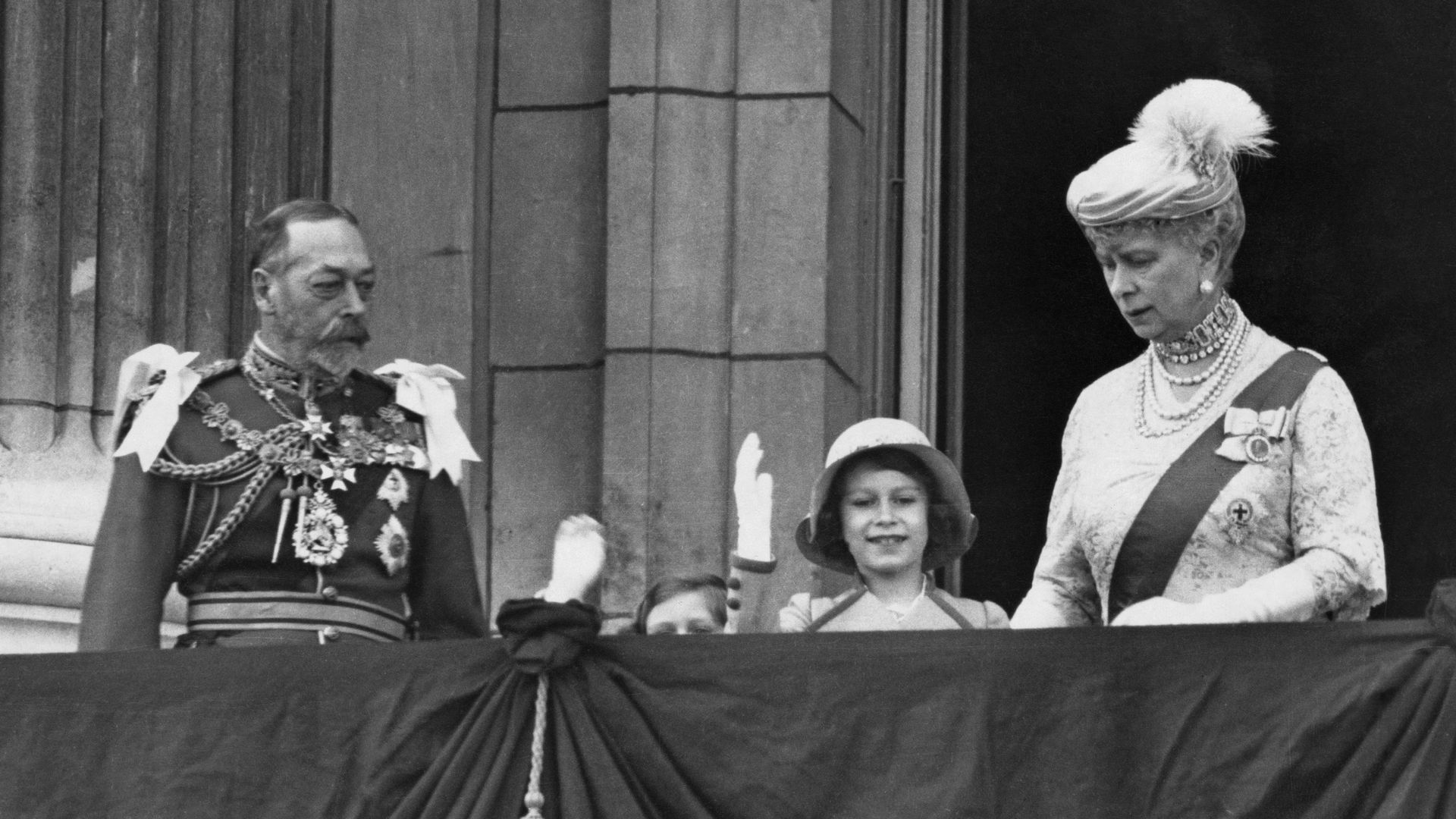 Black and white photo of King George V, Princess Margaret, Princess Elisabeth and Queen Mary on Buckingham Palace balcony