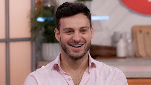 Vito Coppola sitting on a sofa in a pink shirt