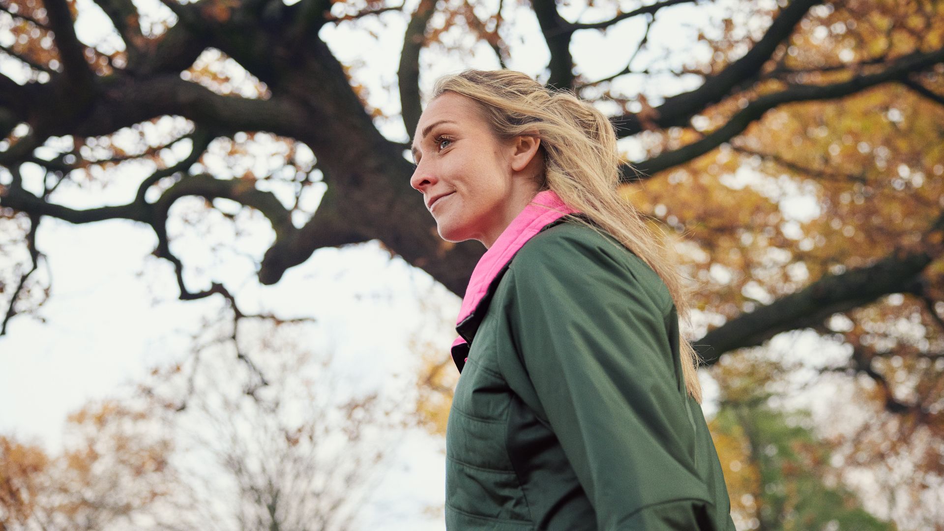 Woman in pink and green jacket outside during autumn