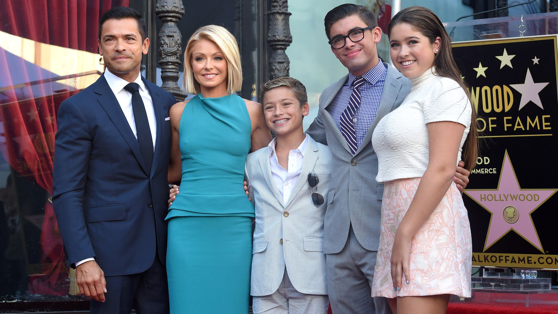 Kelly, Mark and their three children smiling on a red carpet
