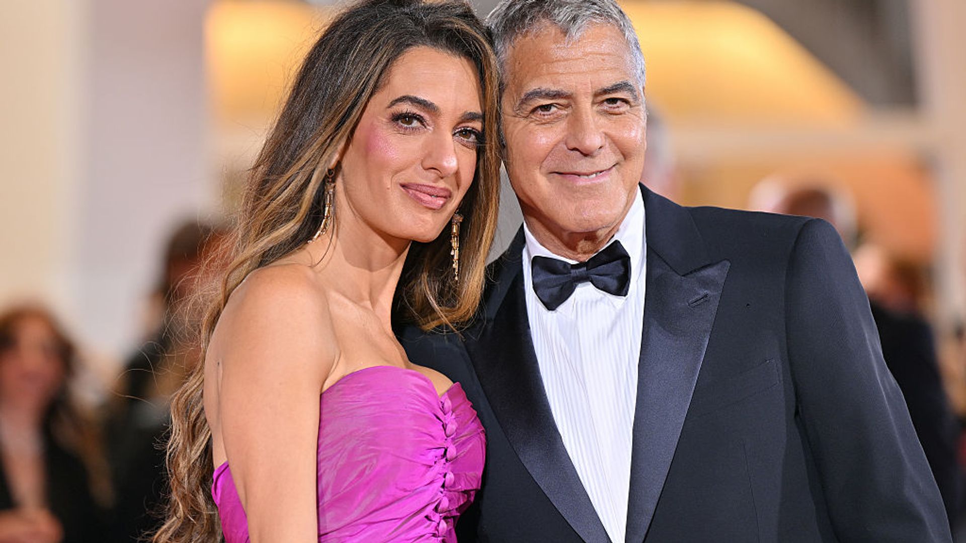 George Clooney and Amal Clooney (with her honey-toned locked and fuchsia dress) at the Venice International Film Festival