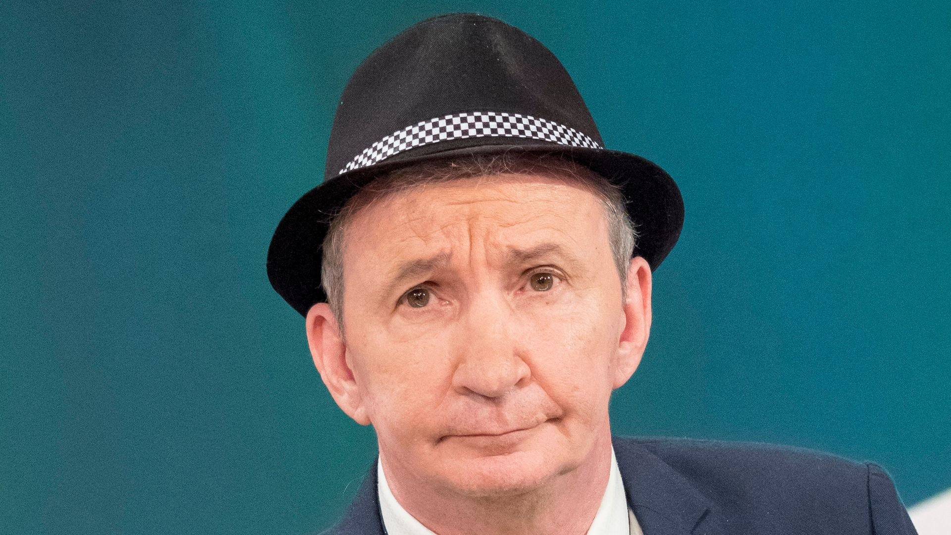 man in suit and hat in tv studio