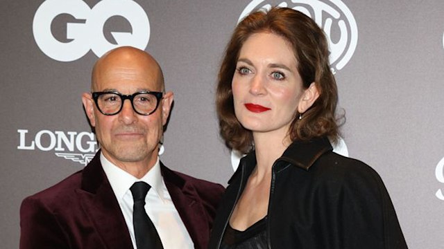 Stanley Tucci in a burgundy velvet suit and Felicity Blunt in a black dress at a red carpet event for GQ