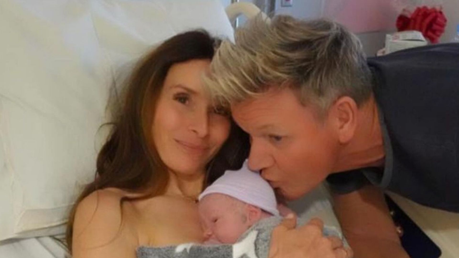 Tana Ramsay holding a newborn baby close to her chest as Gordon Ramsay kisses the baby's head
