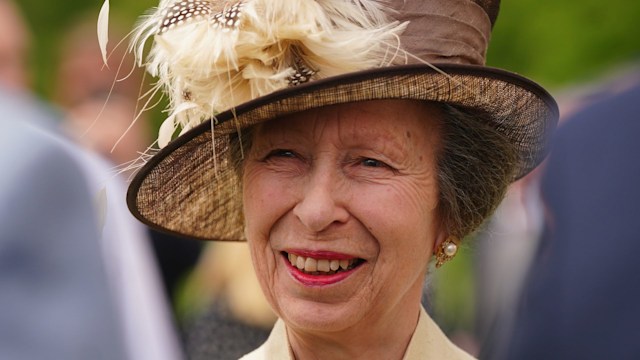Princess Anne wearing feathered hat and red lipstick at palace garden party