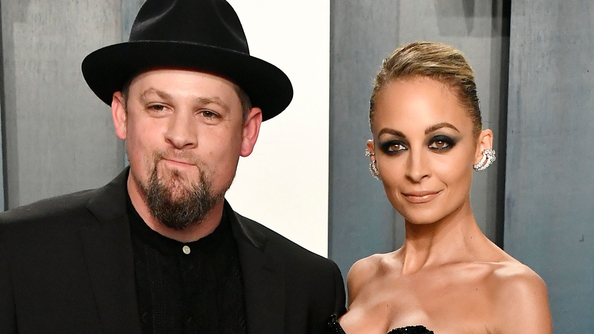 Joel Madden in a black suit and hat with Nicole Richie in a strapless black dress