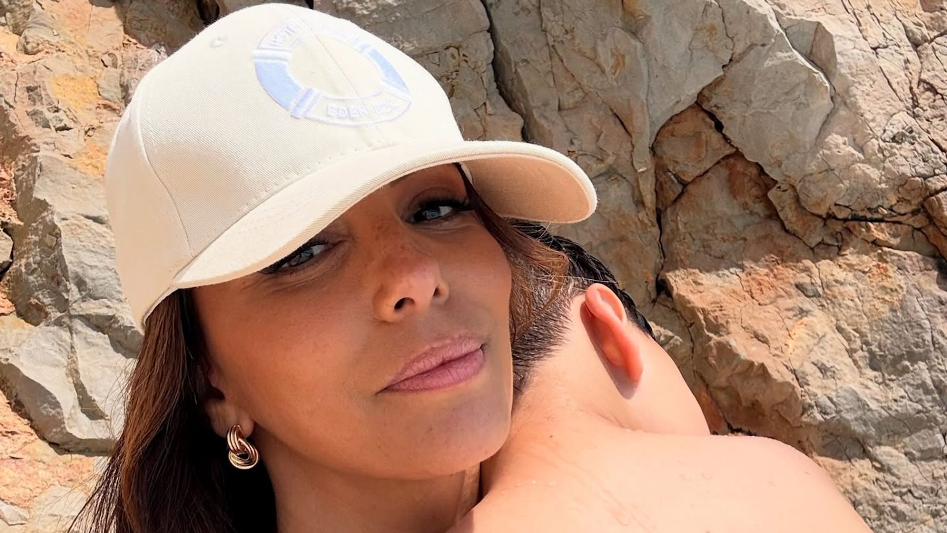 eva Longoria in baseball cap with son on shoulder
