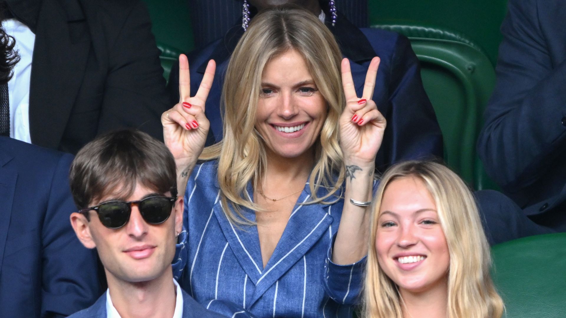 Lila Moss and Yoni Helbitz sat in the crowd at Wimbledon with Sienna Miller in the background doing the peace sign 