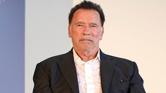arnold schwarzenegger sitting on stage with a mic