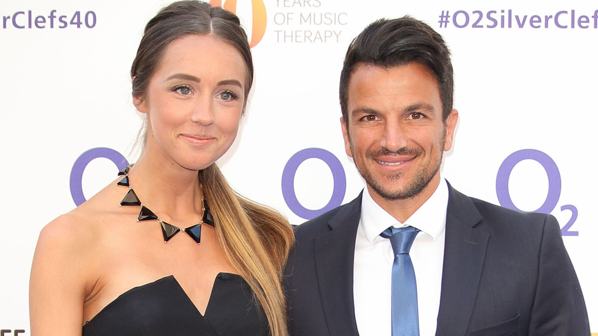 Emily Andre in a white dress standing with Peter Andre in a suit