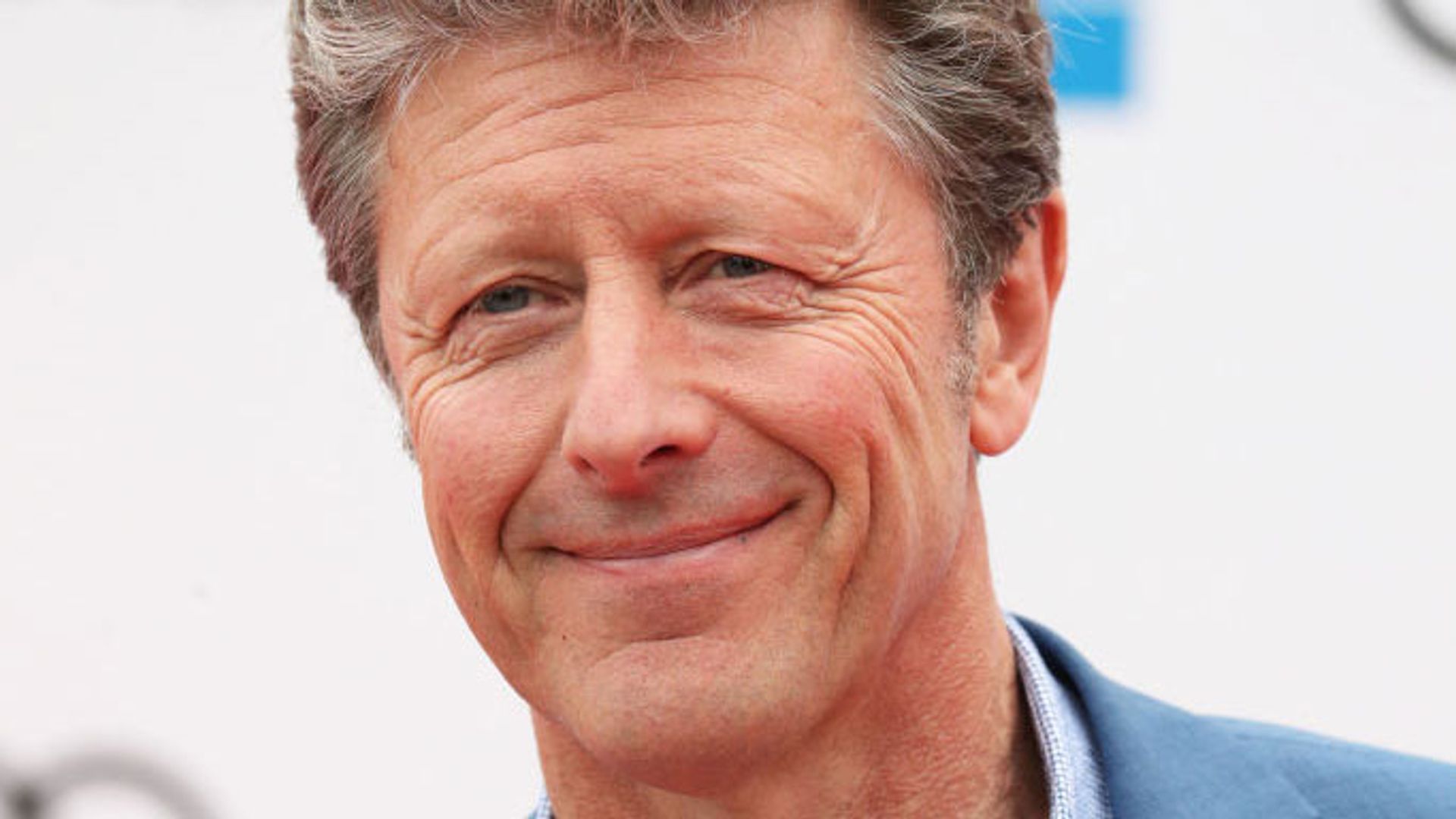 Close up of Charlie Stayt smiling in a pale blue suit. 