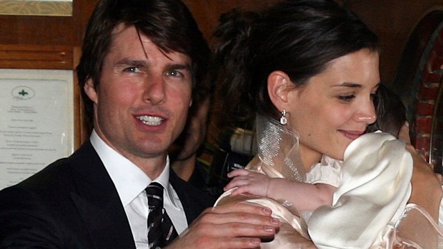 Tom Cruise in a suit and Katie Holmes hugging baby Suri