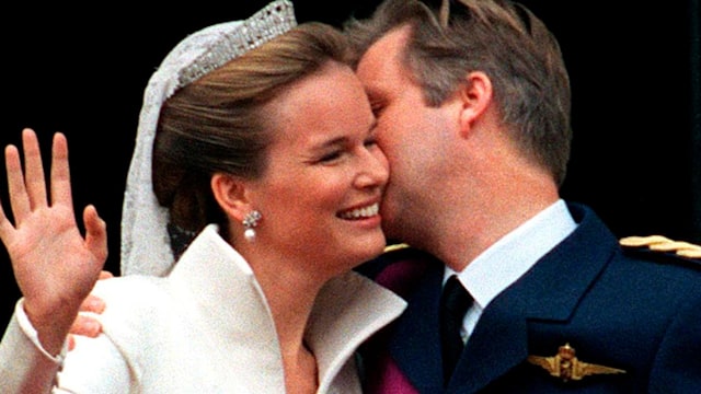 King Philippe kissing his bride Queen Mathilde on the cheek while she waves