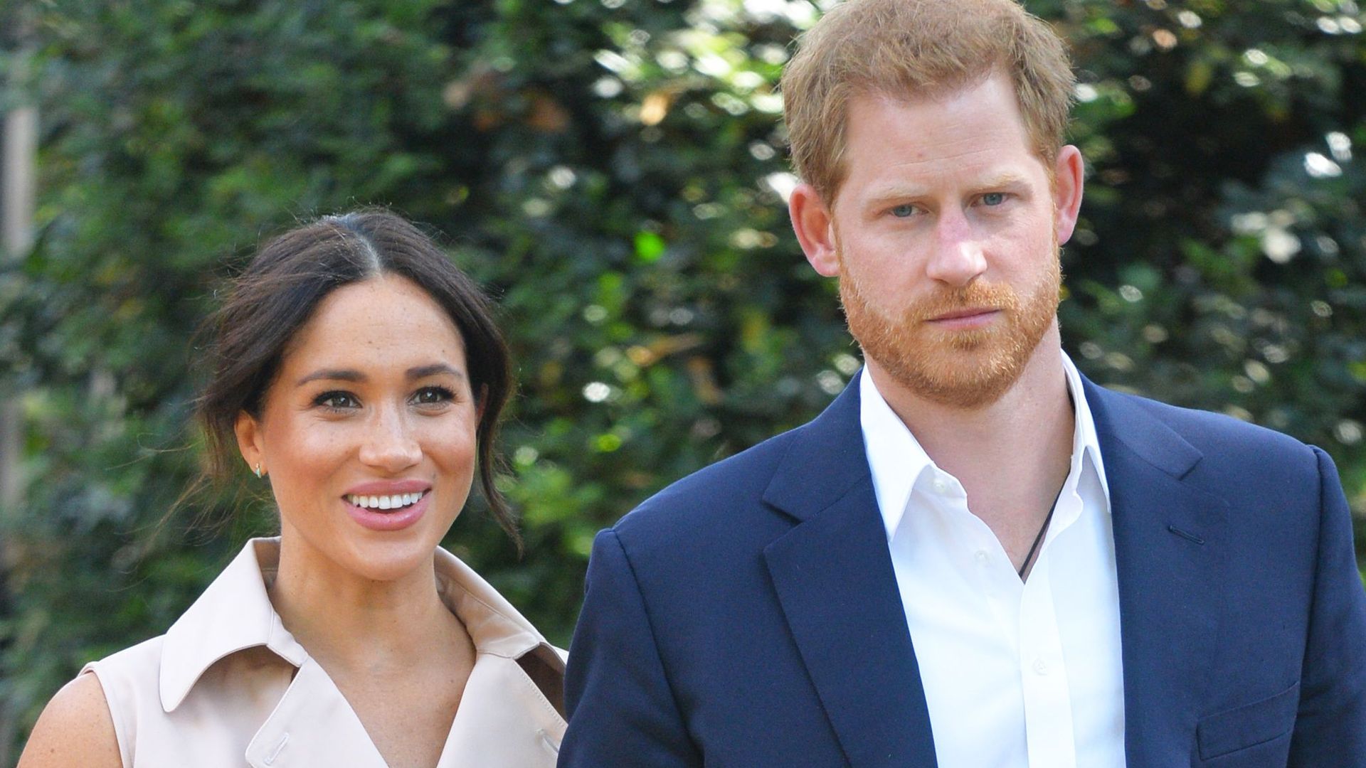 Prince Harry in a blue suit and Meghan Markle in a belted dress