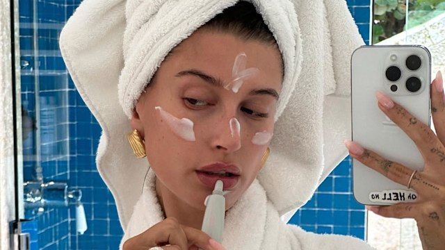 hailey bieber wearing towel applying skincare.