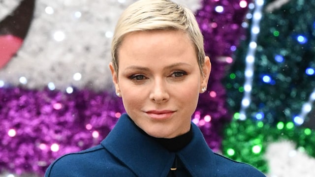 Princess Charlene in a blue jacket in front of glitter