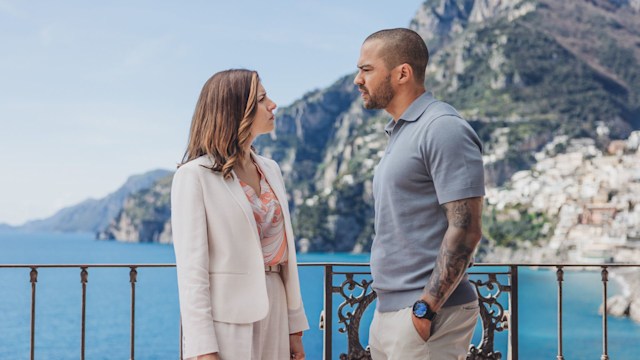 woman and man looking at each other on balcony in front of mountain