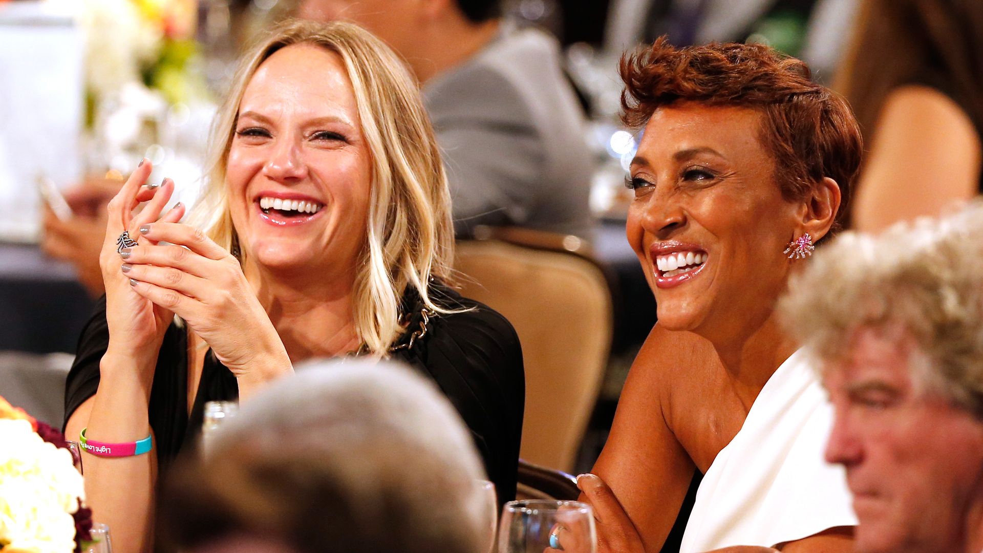 Robin Roberts and Amber Laign smiling sat at a table during an event