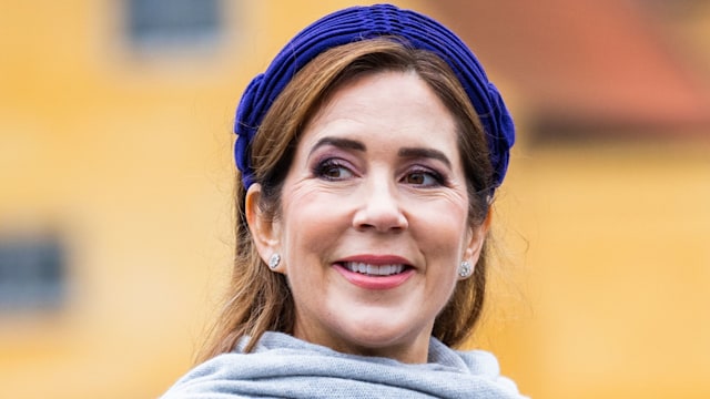 Queen Mary in purple dress and headband with grey shawl