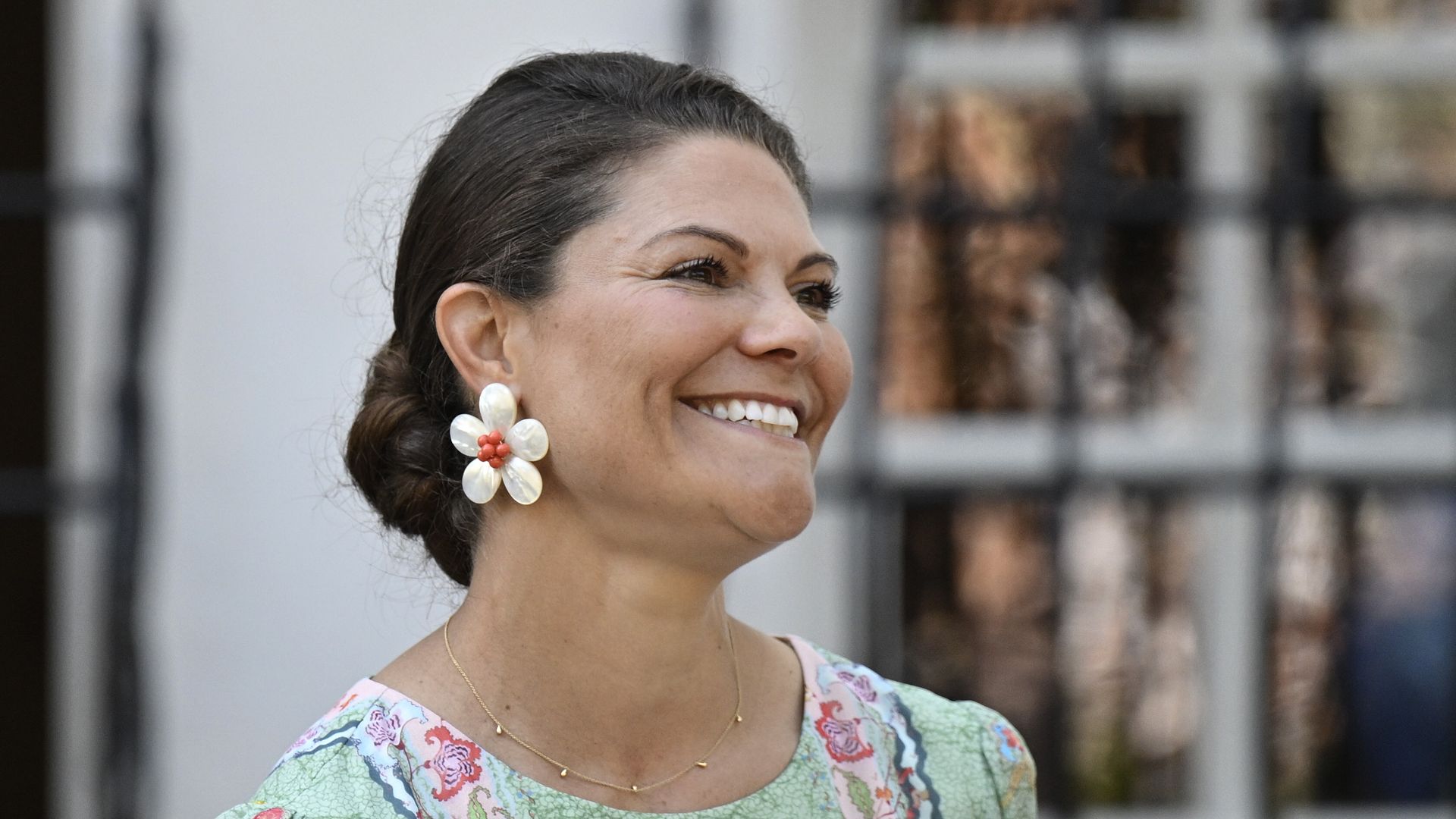 Crown Princess Victoria smiling in green dress and flower earrings