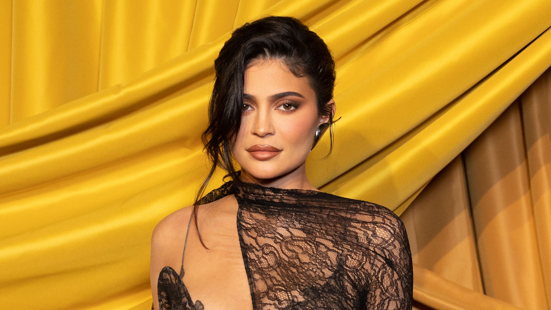 Kylie Jenner wearing an asymmetric lace dress at Paris Fashion Week 