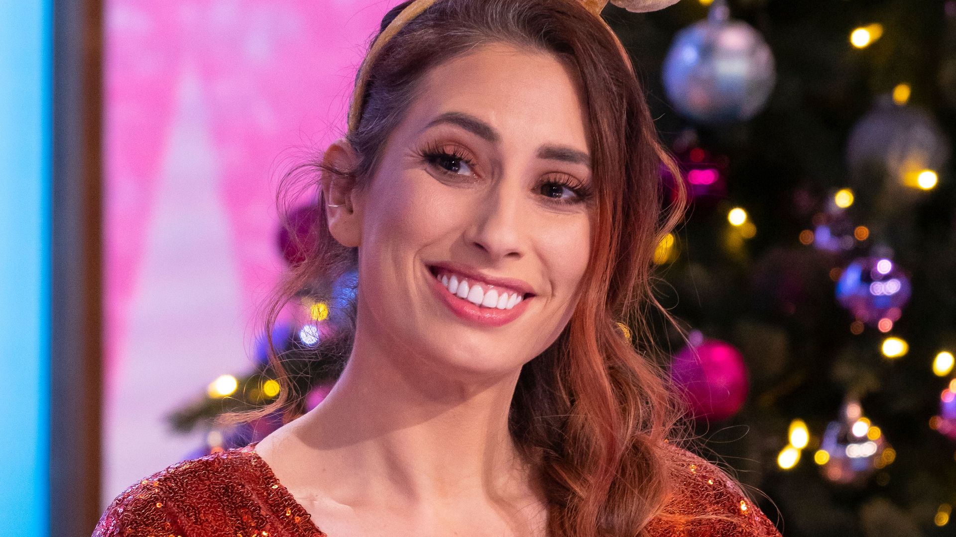 Stacey Solomon in a sparkly red dress in front of a Christmas tree