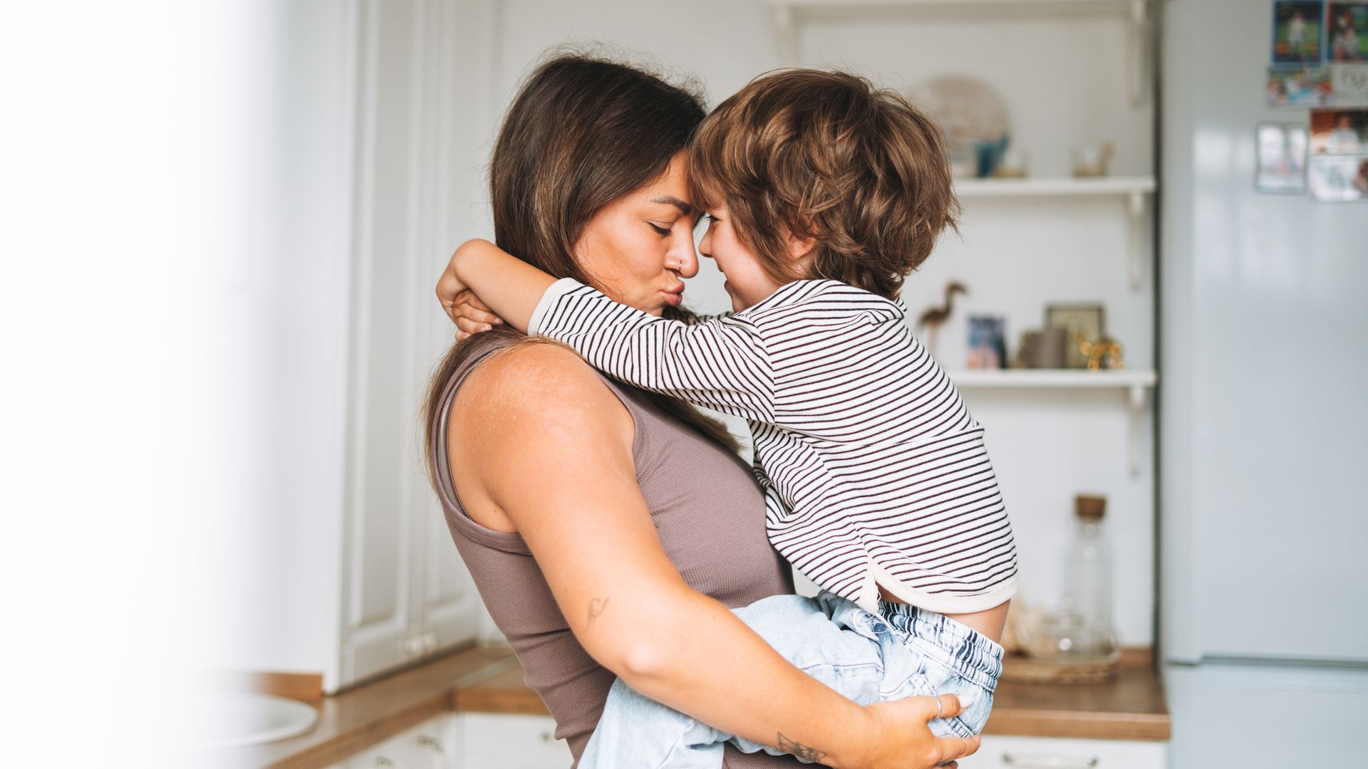woman hugging her son boy in arms in kitchen at home