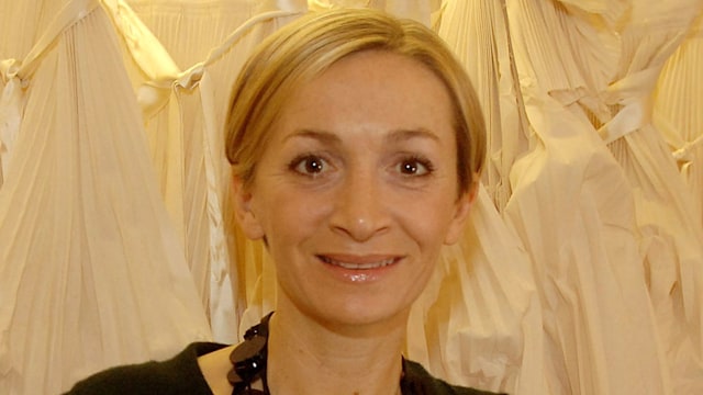 Anna Valentine smiling in front of a row of dresses