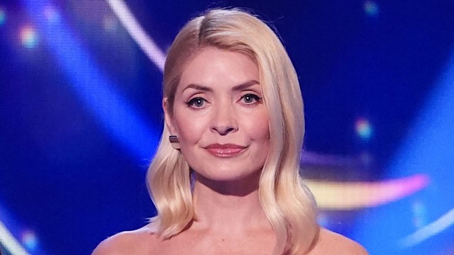 Holly Willoughby with expressionless face in a black and silver dress