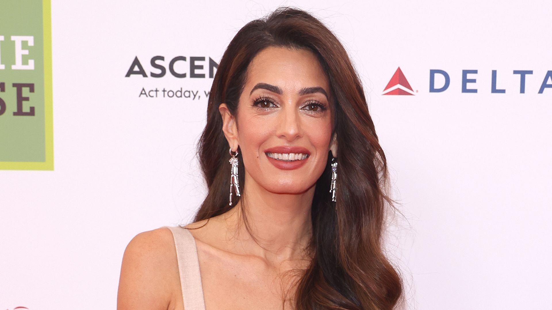 Amal Clooney smiling at a red carpet event