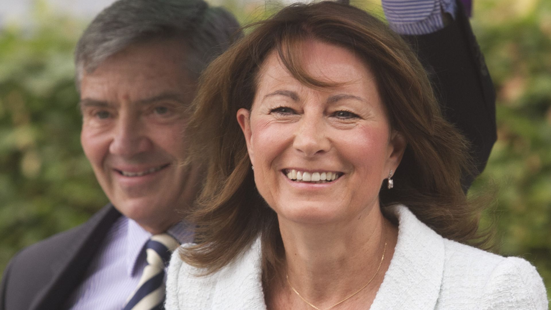 Carole Middleton in a white coat under an umbrella with Michael