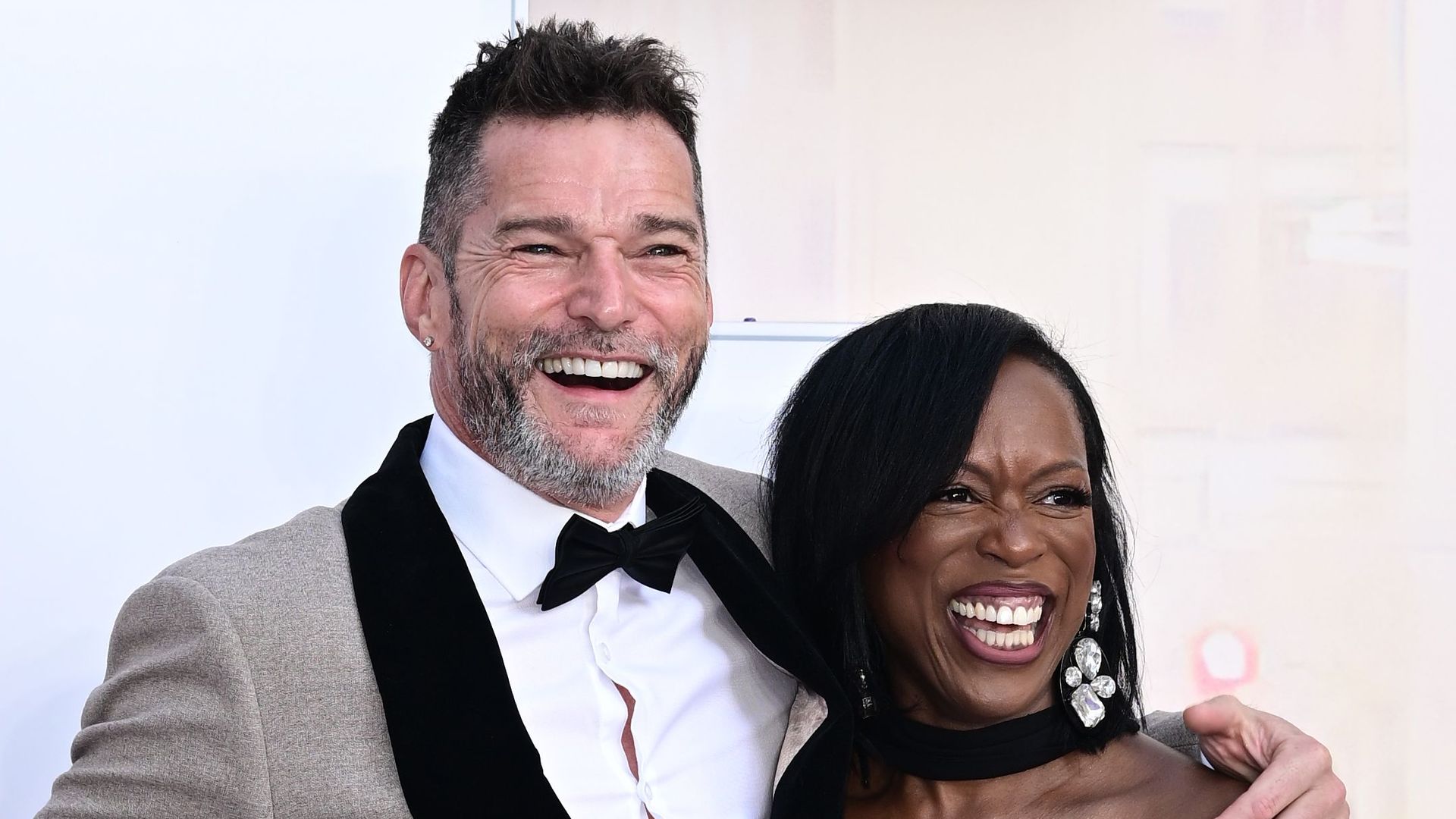 Man and woman with arms around each other smiling for photos