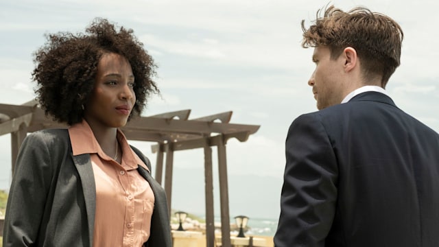 Woman in suit looking at man in suit standing on beach
