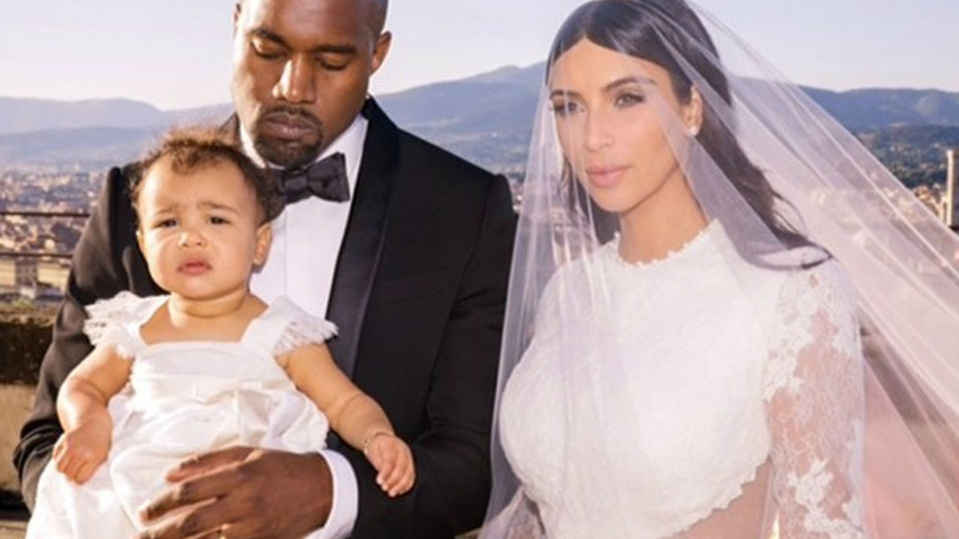 kim kardashian in her wedding dress next to kanye who is holding their baby daughter north west