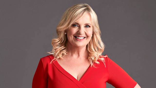 Carol Kirkwood smiling while wearing a red short-sleeved dress with her blonde hair worn loose