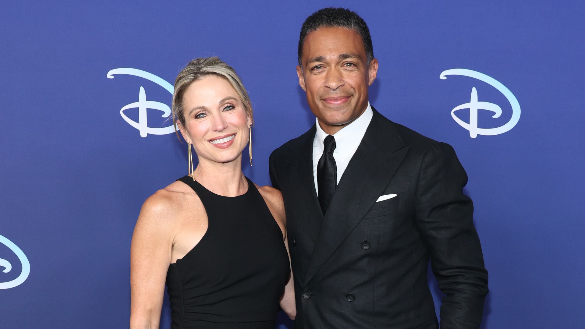 Amy Robach in a black dress and TJ Holmes in a suit