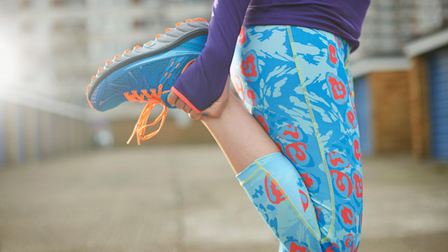 Cropped view of woman bending leg and stretching before exercise