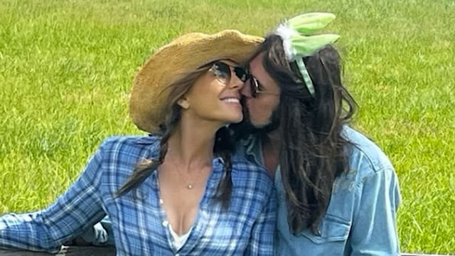 Billy Ray Cyrus in a denim shirt kissing Elizabeth Hurley in a plaid outfit