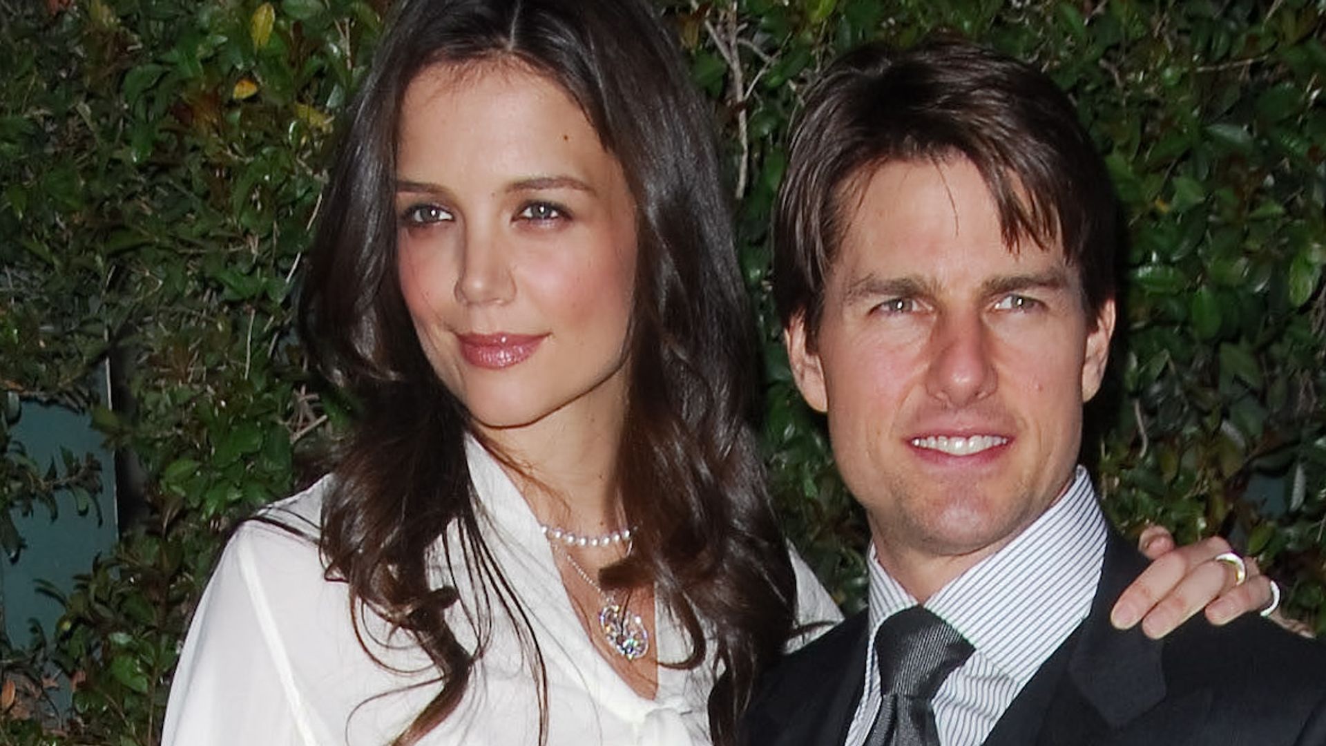 Katie Holmes in a black skirt and shirt with Tom Cruise