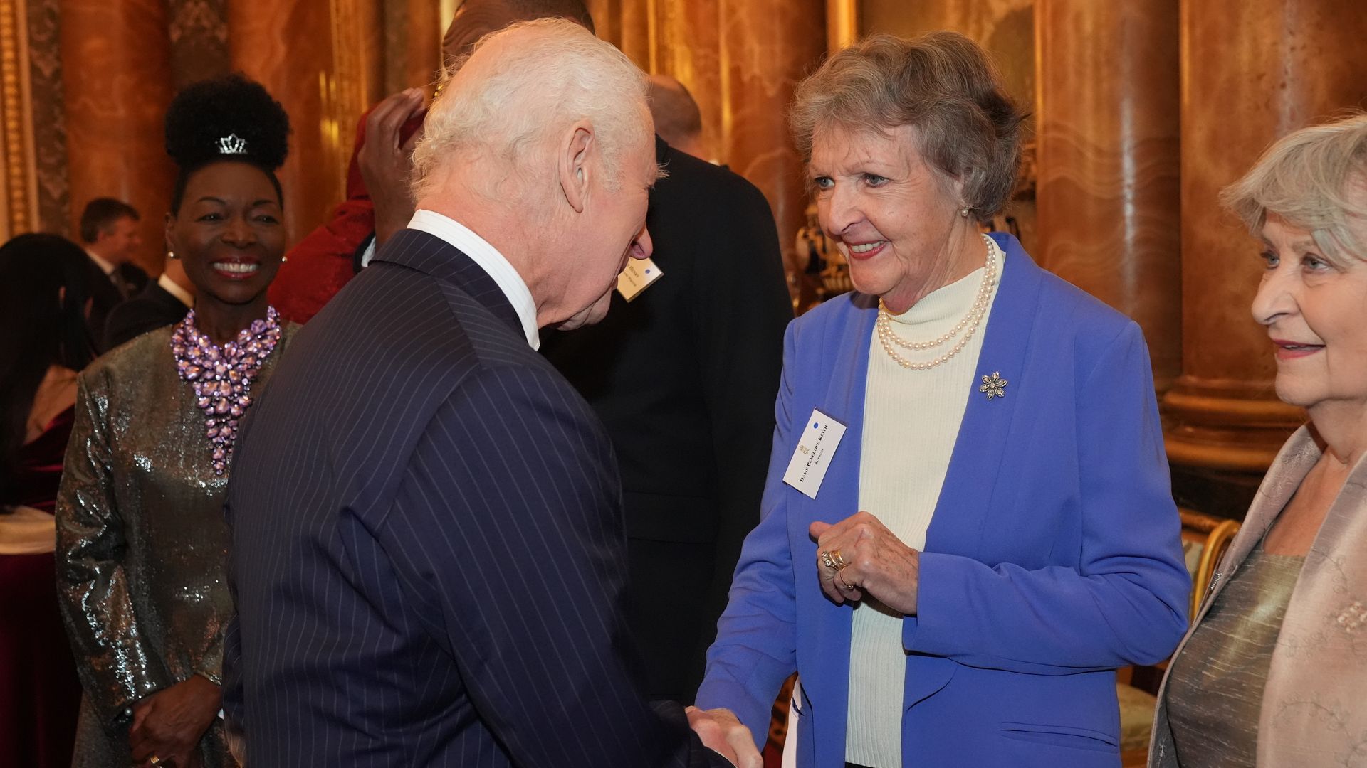 King Charles shaking hands with Penelope Keith