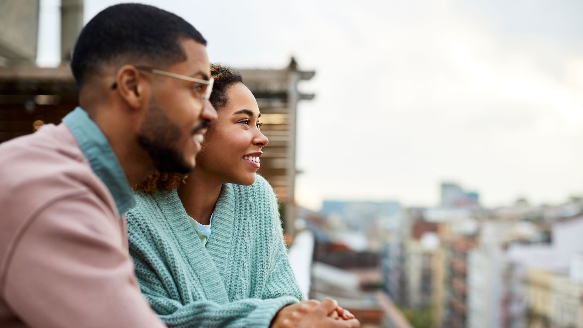 Couple Looking Away While Holding Hands At Rooftop