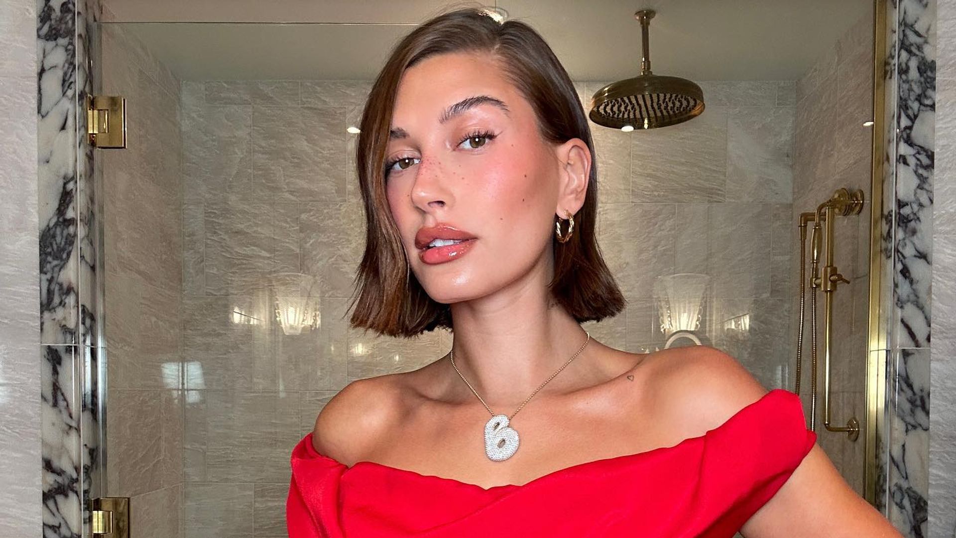Hailey Bieber poses in a red dress in a bathroom