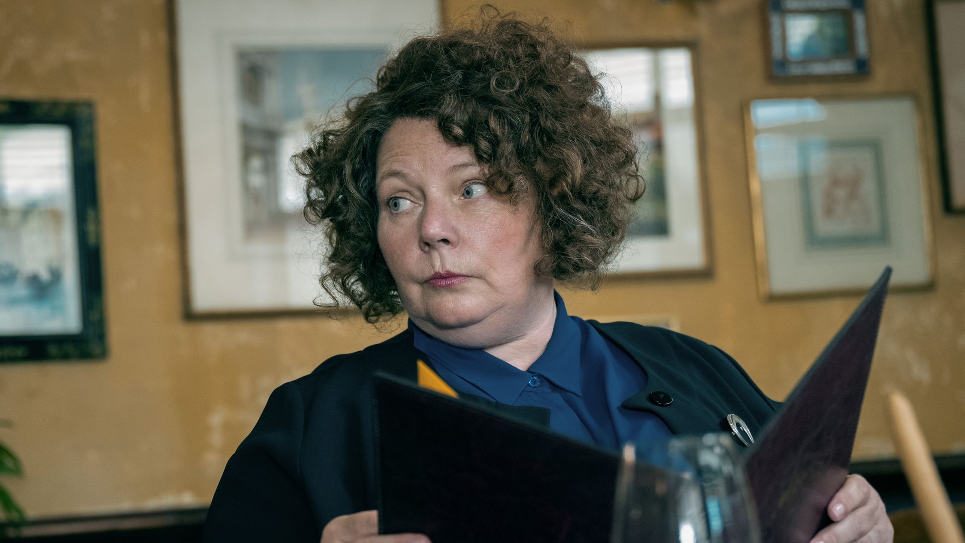 woman sitting at white cloth table holding menu