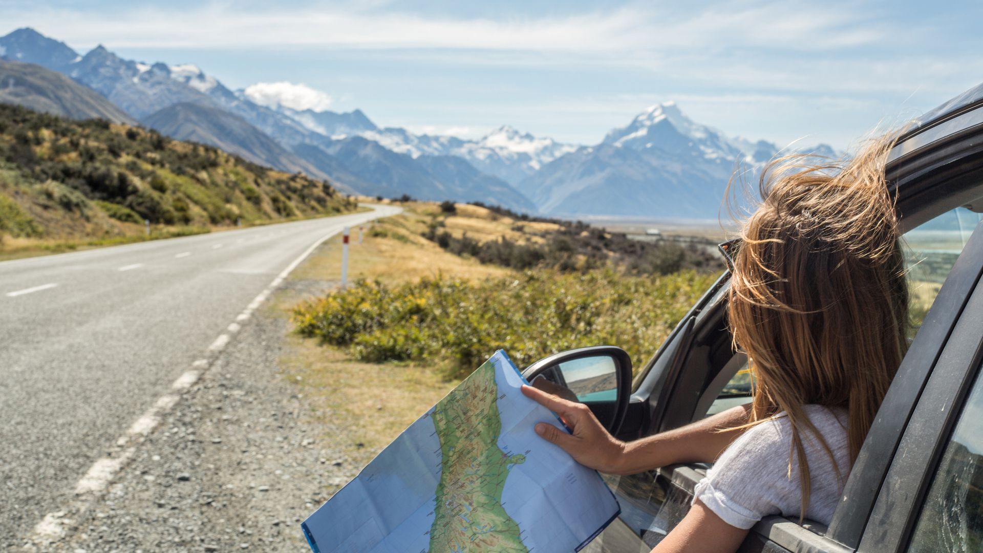 Portrait of young woman in car looking at map