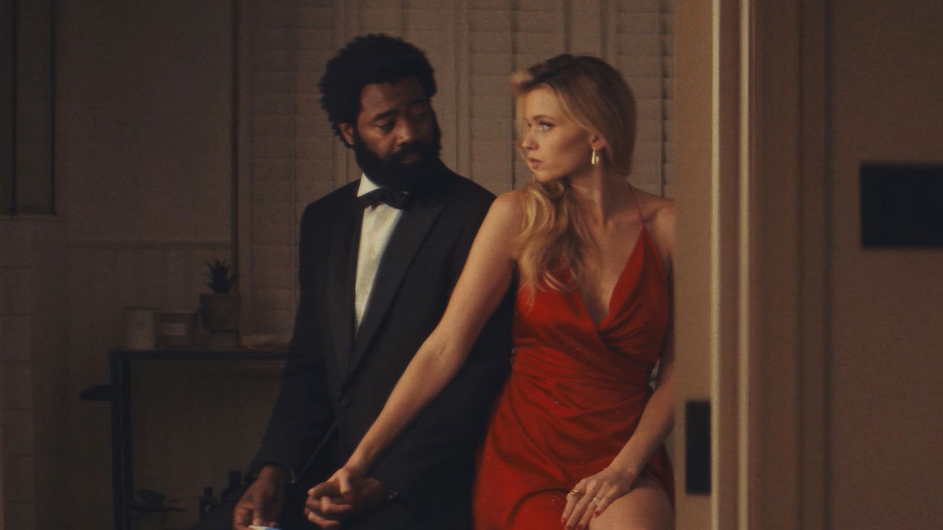 man in suit, woman in red dress in house