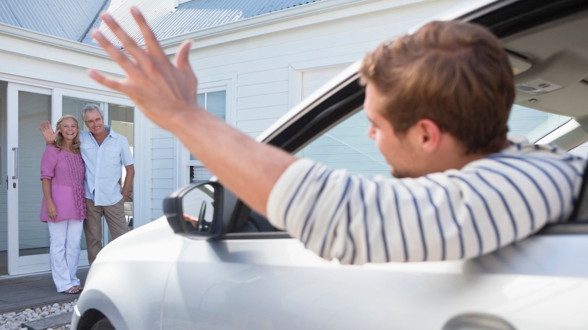 Young man in car waving goodbye to parents