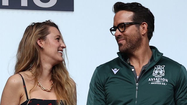 Ryan Reynolds and Blake Lively smiling at eachother while watching soccer