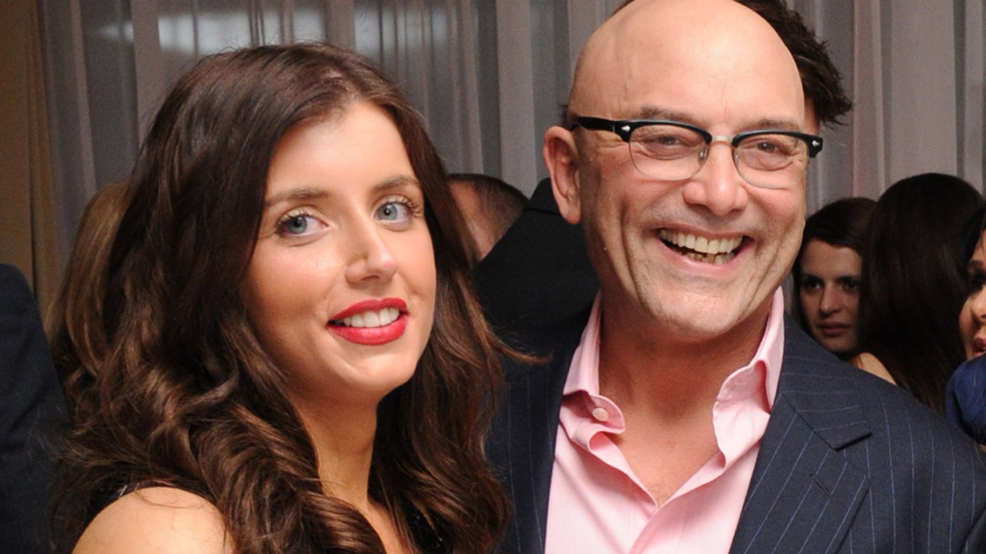 Anne-Marie in a black dress and red lipstick with Greg Wallace in a pinstripe suit and pink shirt
