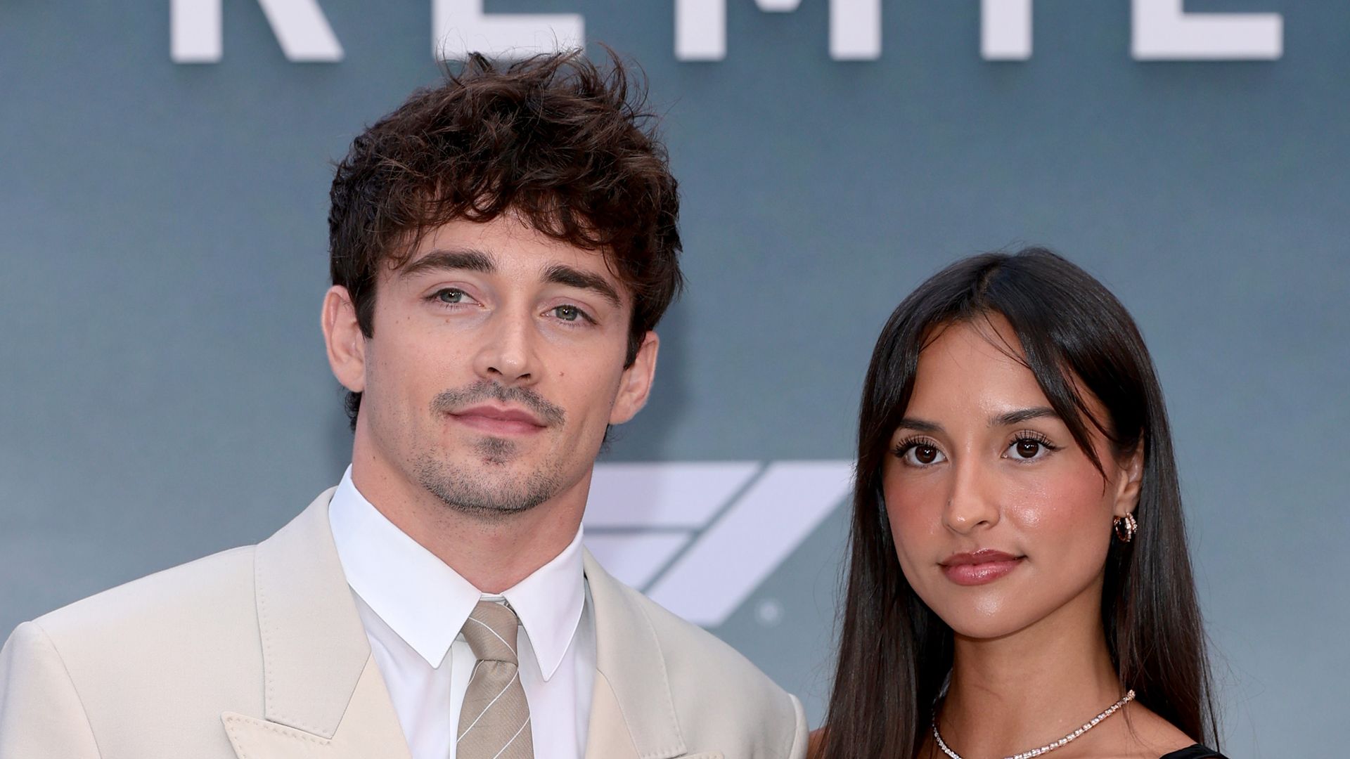Charles Leclerc in a cream suit and Alexandra Saint Mleux in a black dress